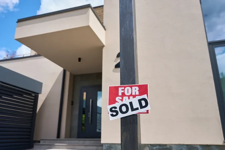 Modern beige home entry with a red for sale sign marked SOLD